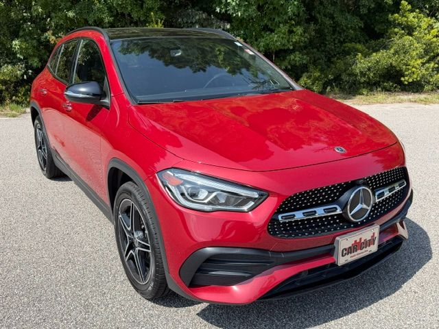 Front-angle view of a red Mercedes-Benz compact SUV parked on an asphalt lot, showcasing the grille and emblem.