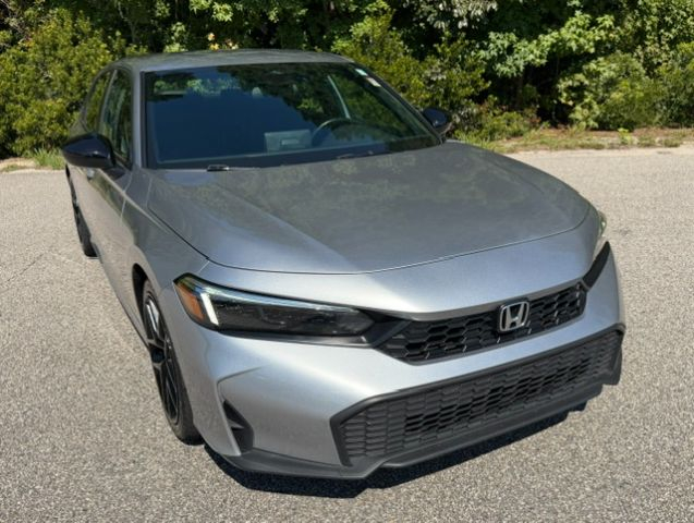 Silver Honda sedan photographed from the front-left, parked on a paved lot with trees in the background.